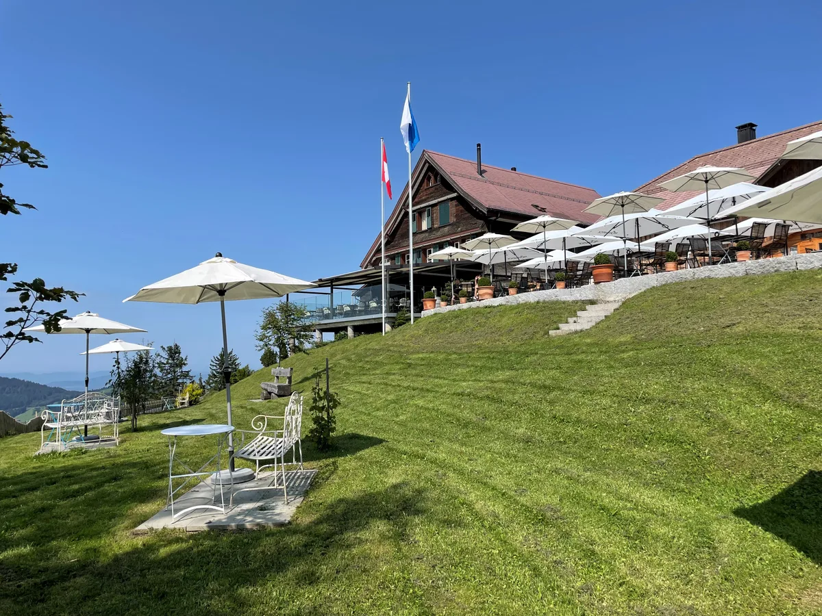 Der Garten vor dem Restaurant Alp Scheidegg ist ebenfalls neu gestaltet worden. Restaurant Alp Scheidegg mit Sonnenschirmen und Wiese.